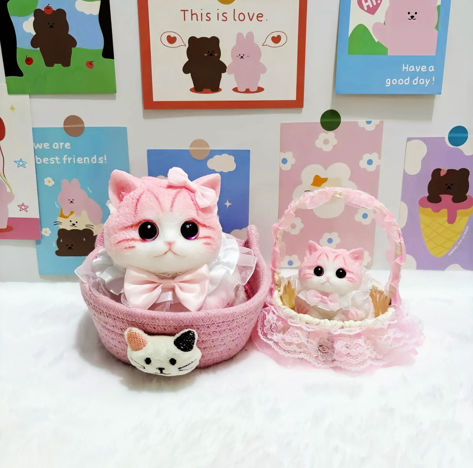 The adorable "Pink_Cat_Lg" fluffy pink and white cat figure wearing a pink bow and ruffled collar, sitting inside a pink woven basket with a cute cat face detail.