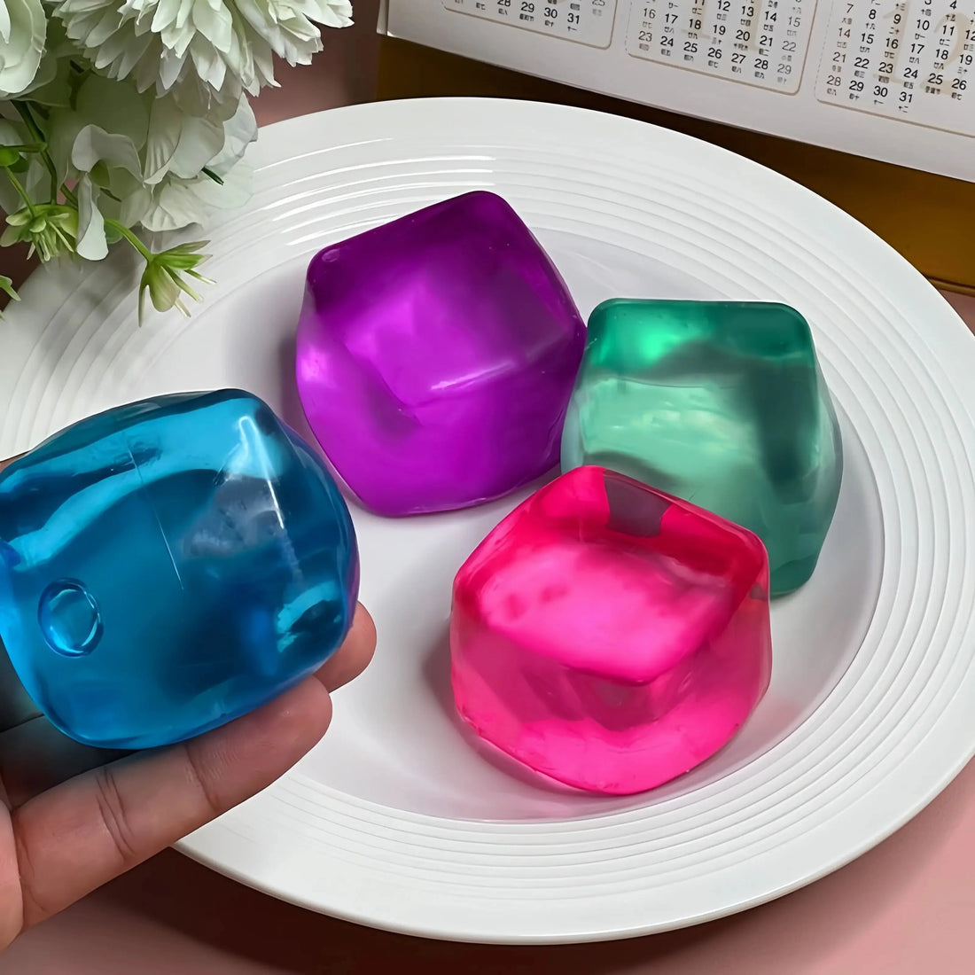 Hand holding colorful soft squishy toys from lovesquishy on white plate