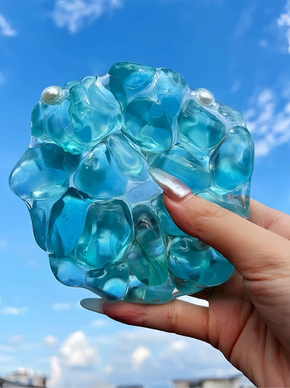 Handmade blue pearl jumbo squishy ball stress relief toy being squeezed outdoors